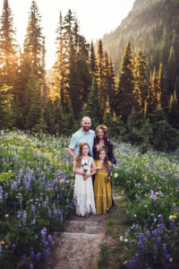 Adventure Family Photography, a small family of four stands on a small trail in the forest amongst wild flowers